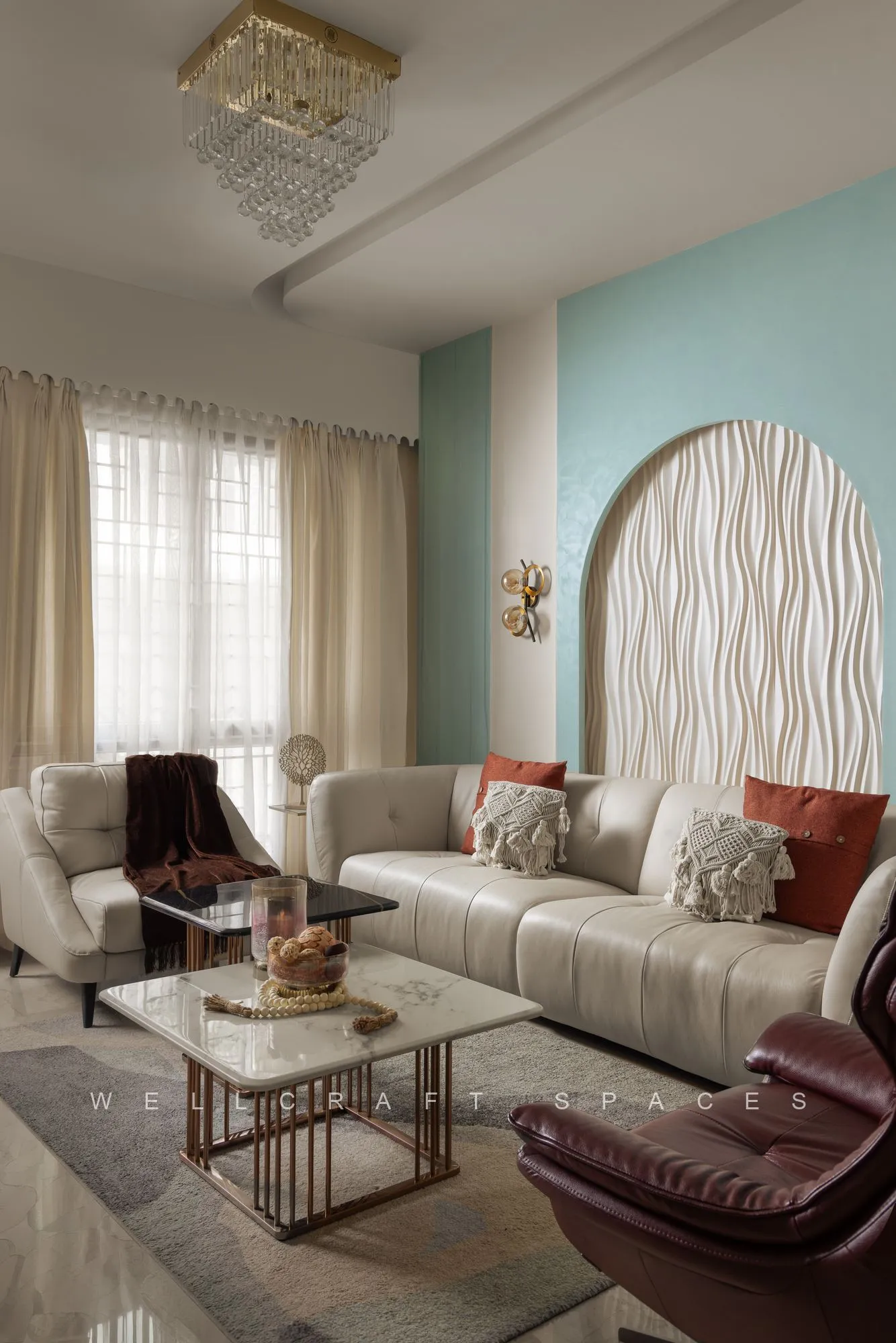 Living room in cream and mint with a ribbed arch panel behind the sofa, an oxblood leather lounge chair and a brass-framed marble coffee table.