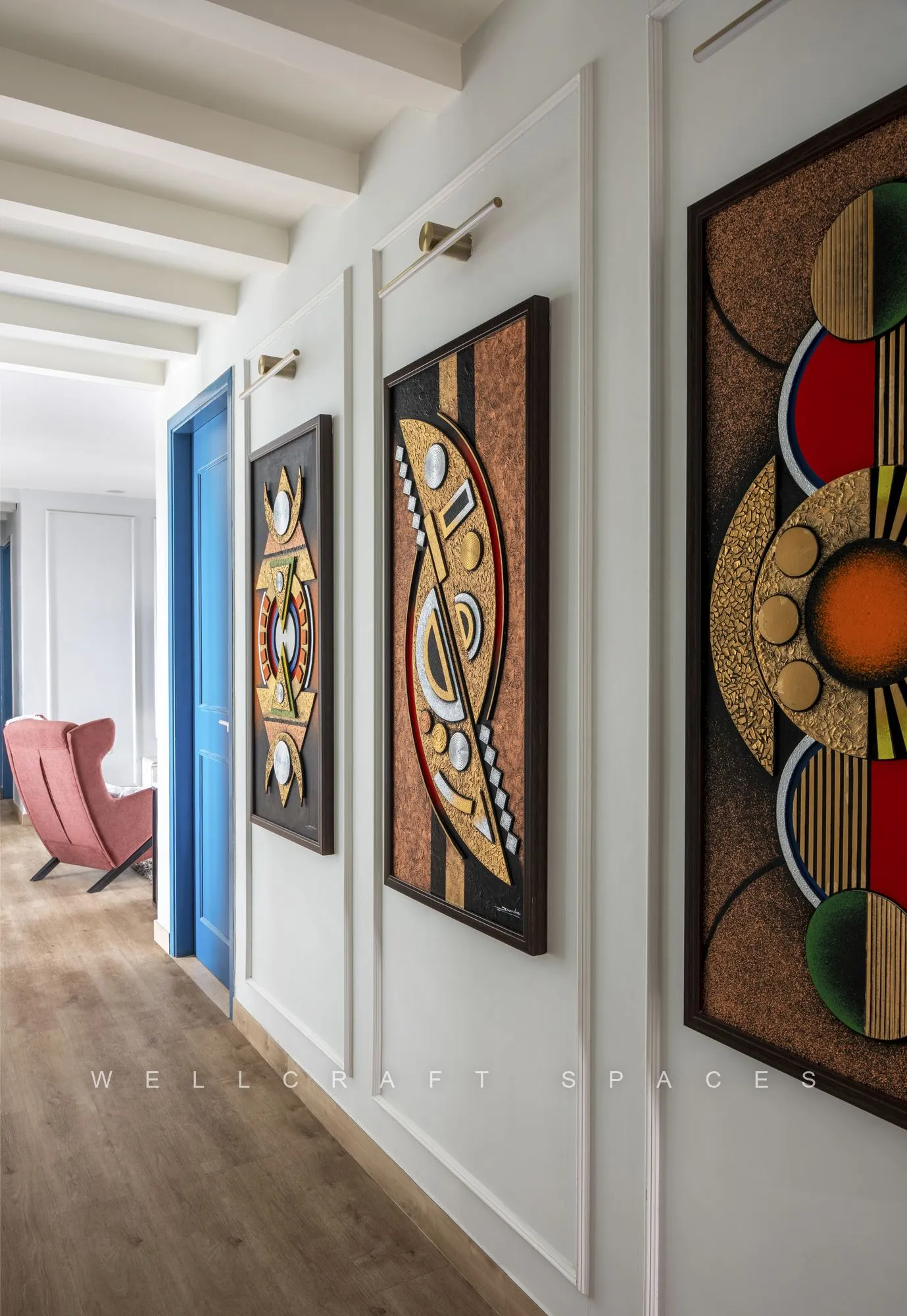 Gallery corridor hung with bold circular abstract canvases against white panelled walls, with a deep blue door at the end of the hall.