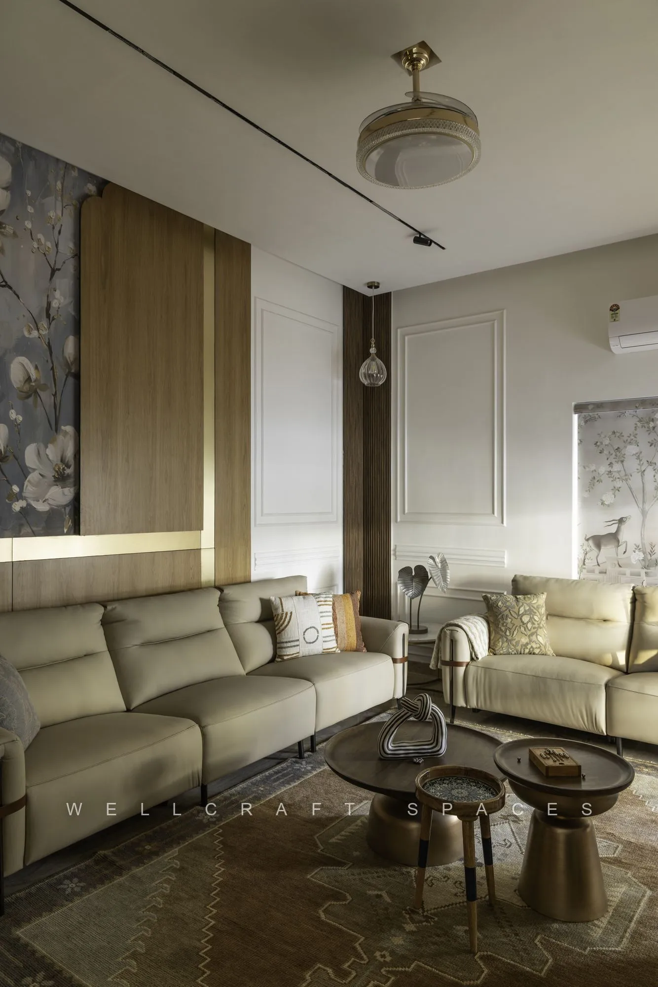 Seating area with a pale olive sofa, nested bronze coffee tables, a fluted timber screen and a circular ceiling light detail.