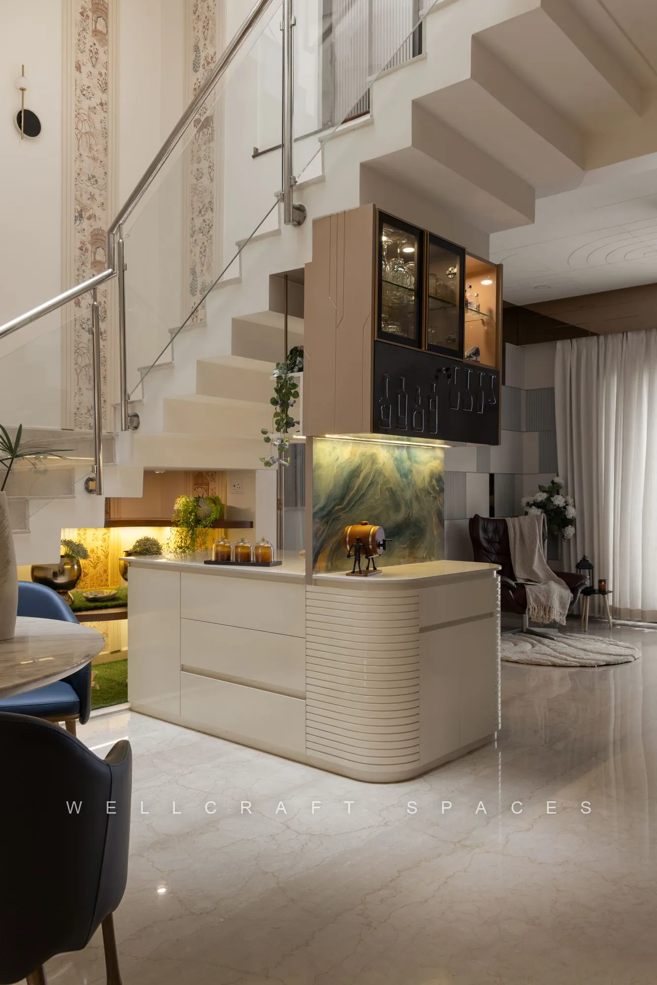 Double-height entry lounge under a curved white staircase, with a ribbed reception counter, navy dining chairs and a backlit display niche.