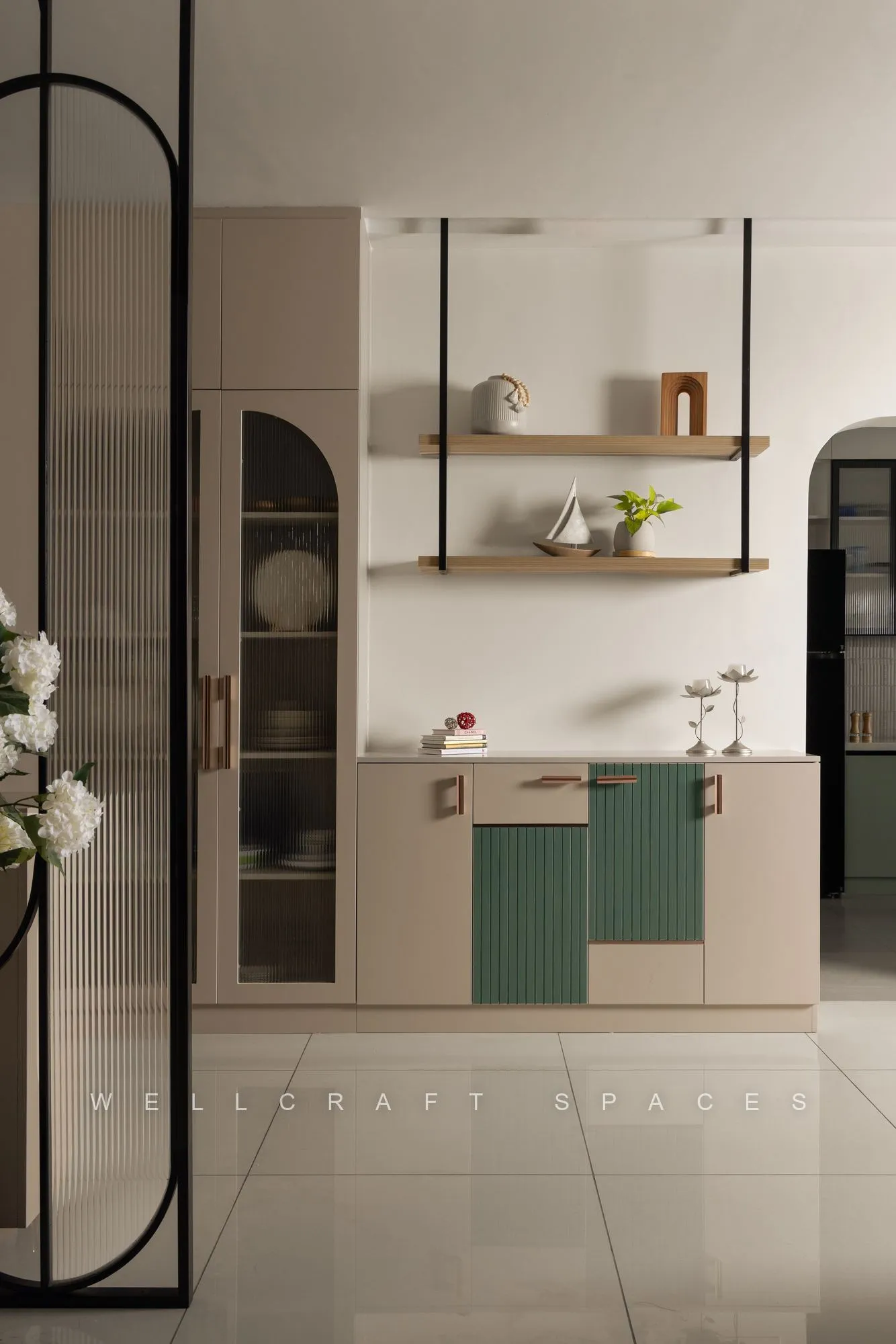 Crockery and bar unit with sage-green fluted shutters, brass-trimmed open shelves and a glass-and-metal partition alongside.
