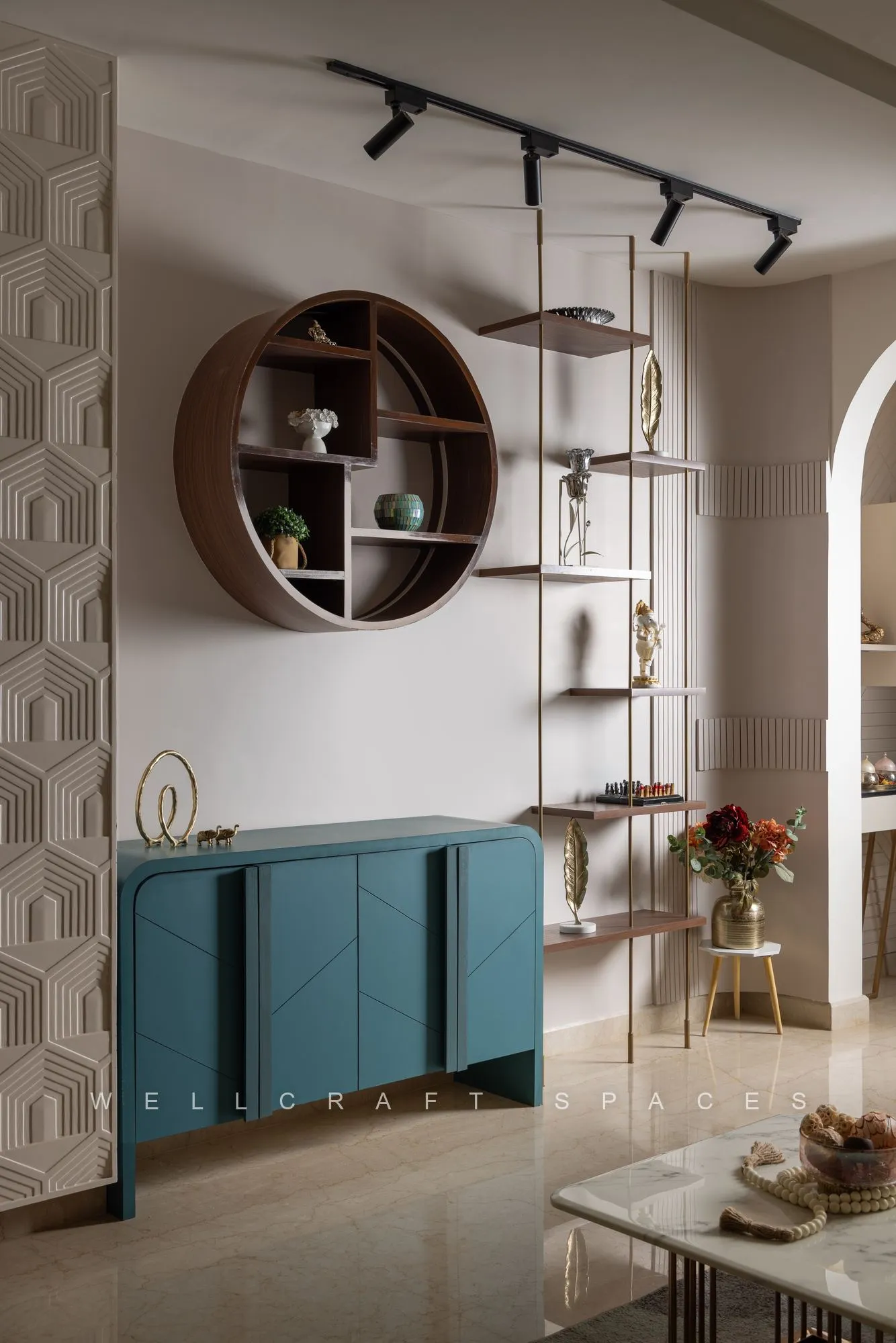 Display wall with a circular walnut shelf, hexagon-patterned panel, teal sideboard and track spotlights above.