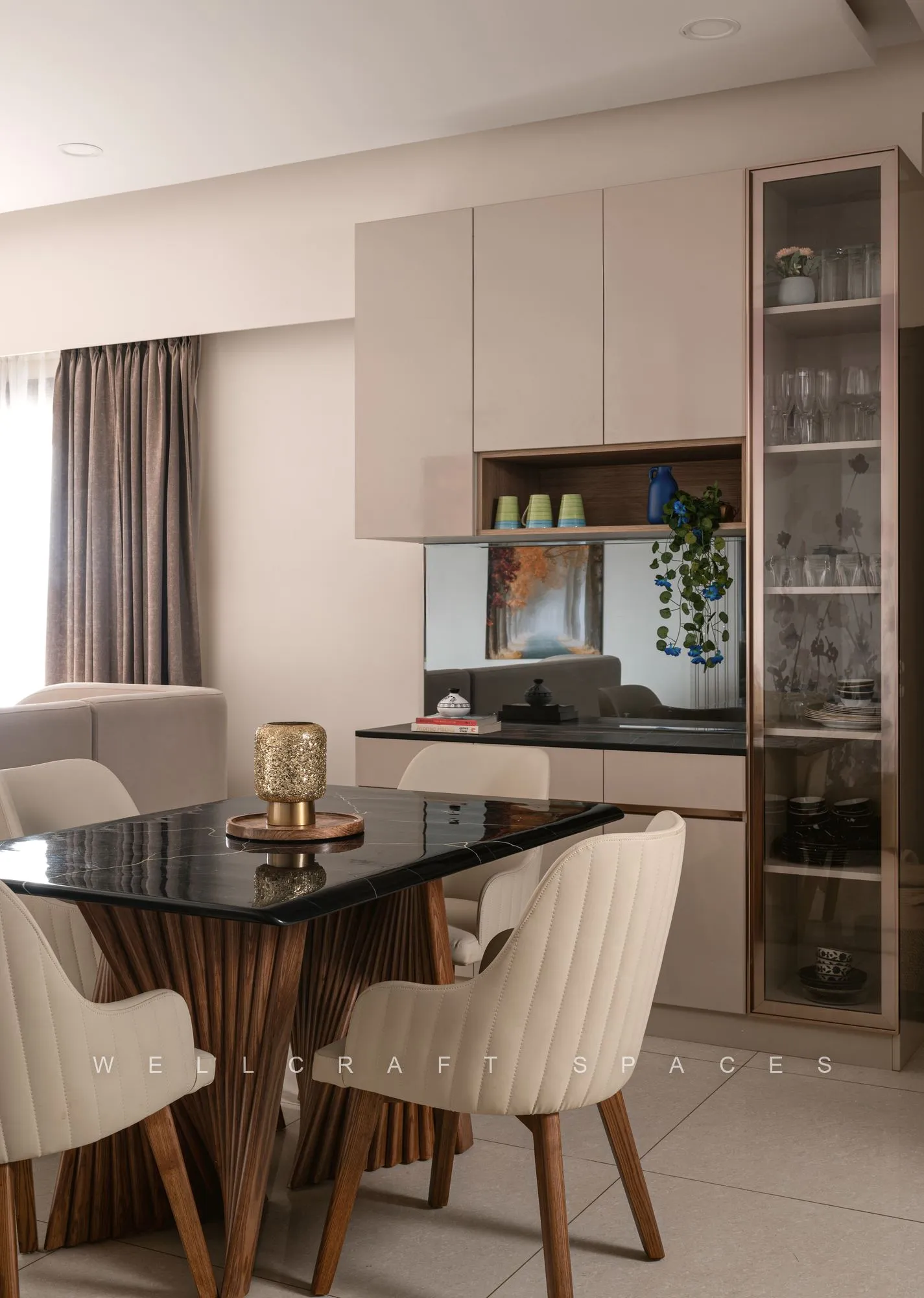 Dining table in smoked glass with tan wood-leg chairs, backed by a glazed crockery unit and the kitchen counter beyond.
