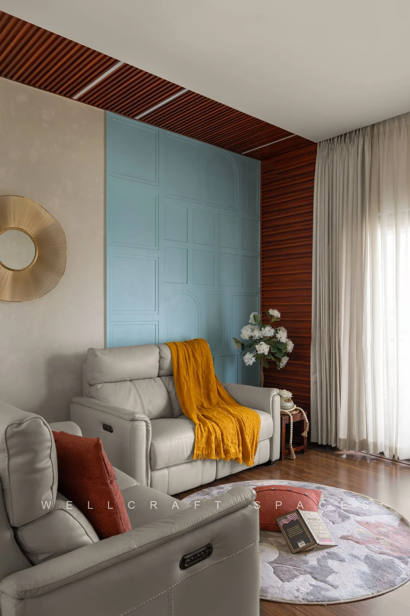 Second living area with a cream recliner, mustard throw, terracotta timber slat wall and a turquoise panel behind the sofa.