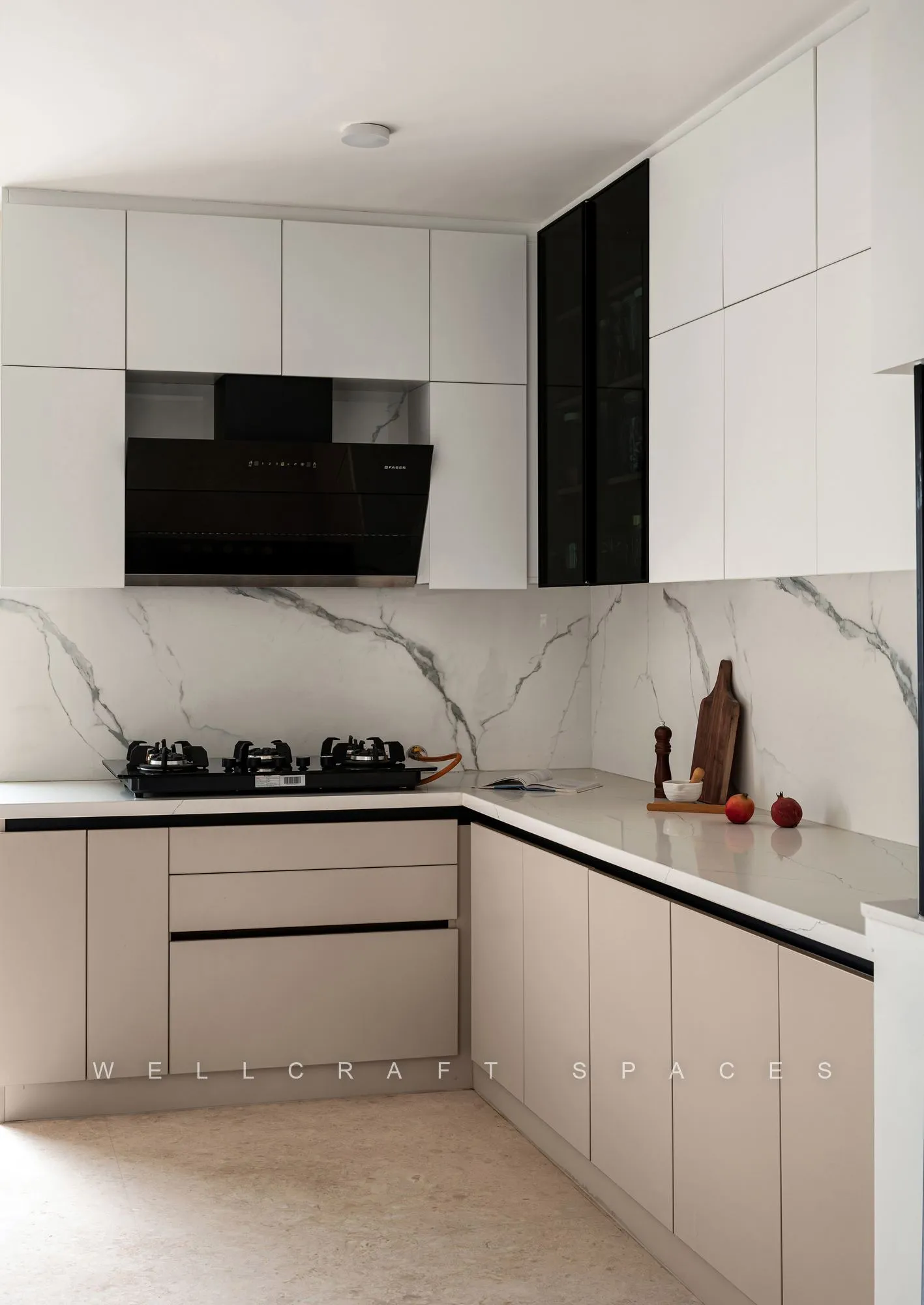 L-shaped kitchen in matt ivory shutters with white quartz counters, a marble-effect backsplash, a black glass chimney and a built-in hob.