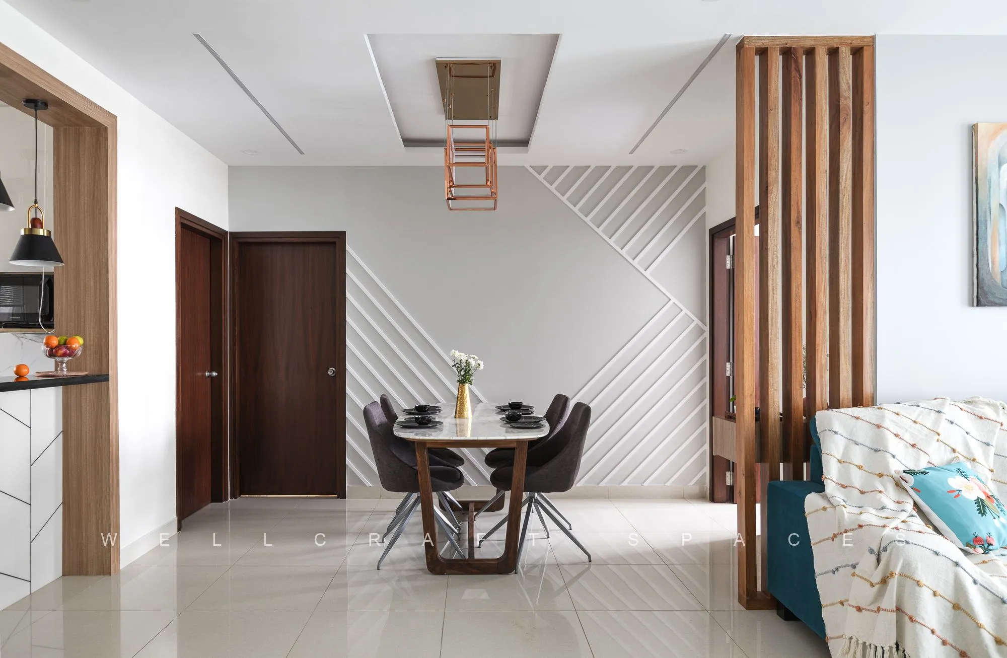 Round dining table with cane-and-black chairs set against a chevron-textured feature wall beside the wooden room divider.