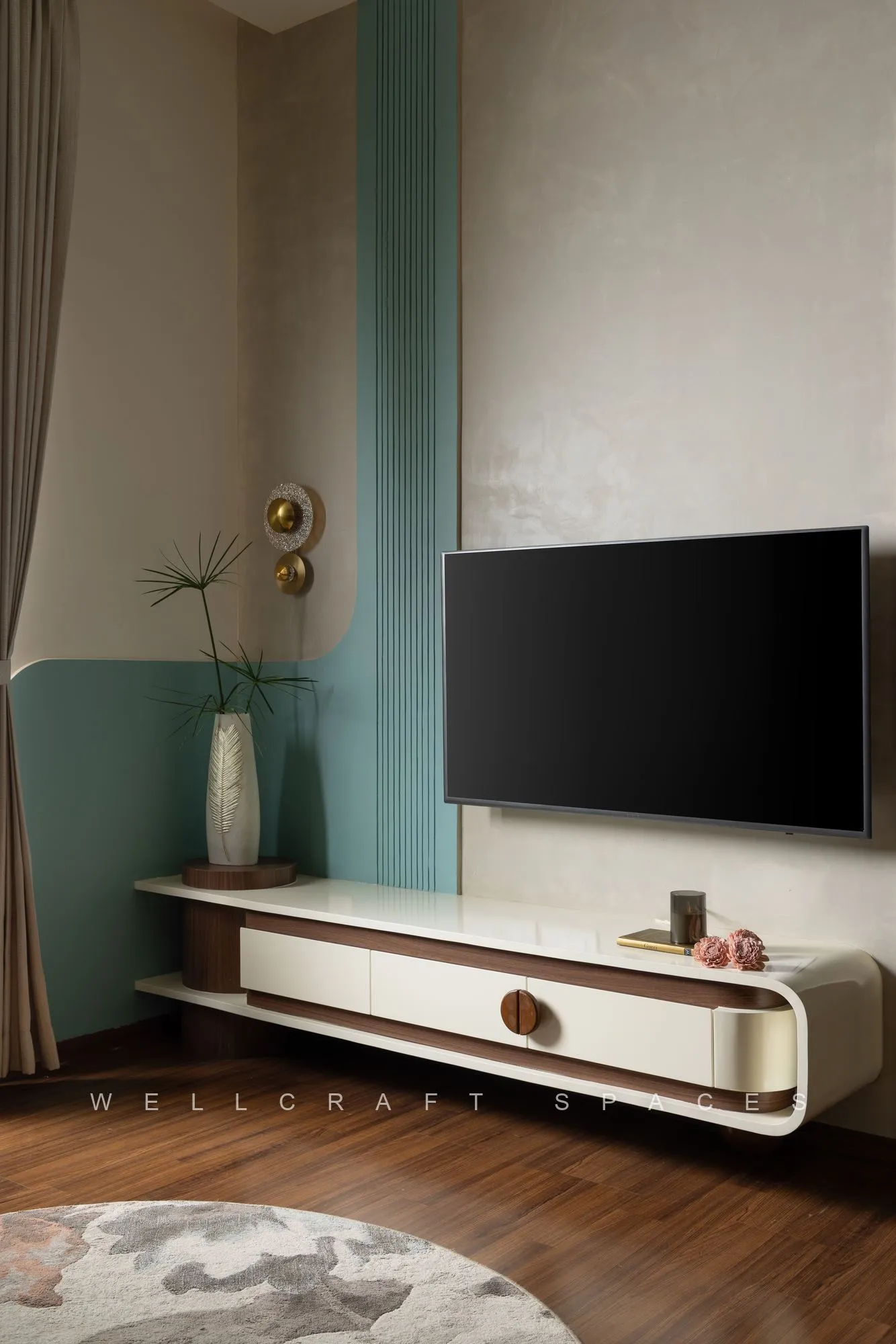 Wall-mounted television on a mint and textured plaster panel above a floating cream and walnut media console.