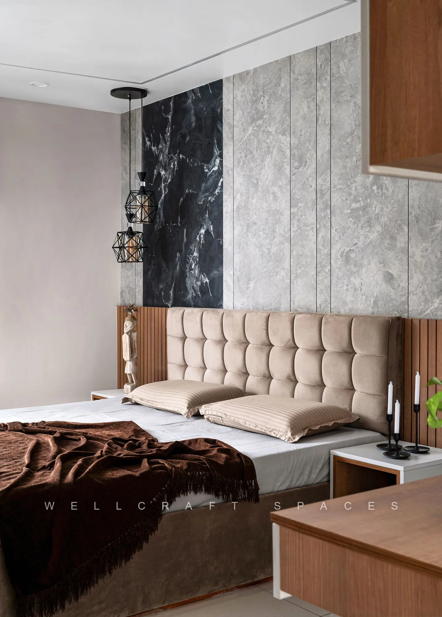 Master bedroom with a buttoned beige leather headboard, chocolate throw, black marble feature panel and a hanging brass lantern beside the bed.