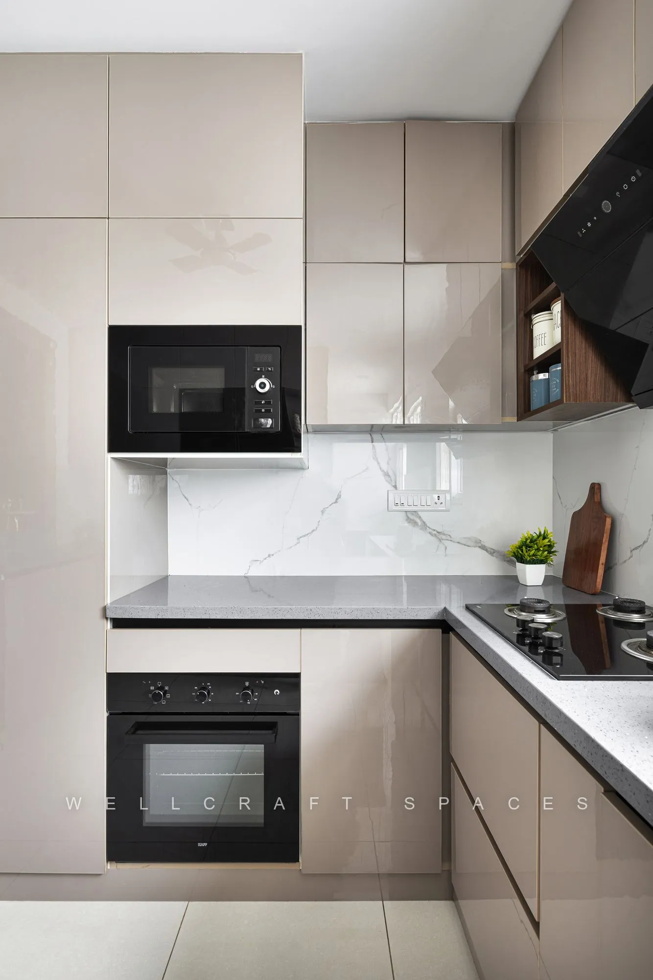 L-shaped kitchen in glossy taupe with a marble-look backsplash, built-in oven and microwave tower and a black granite counter.