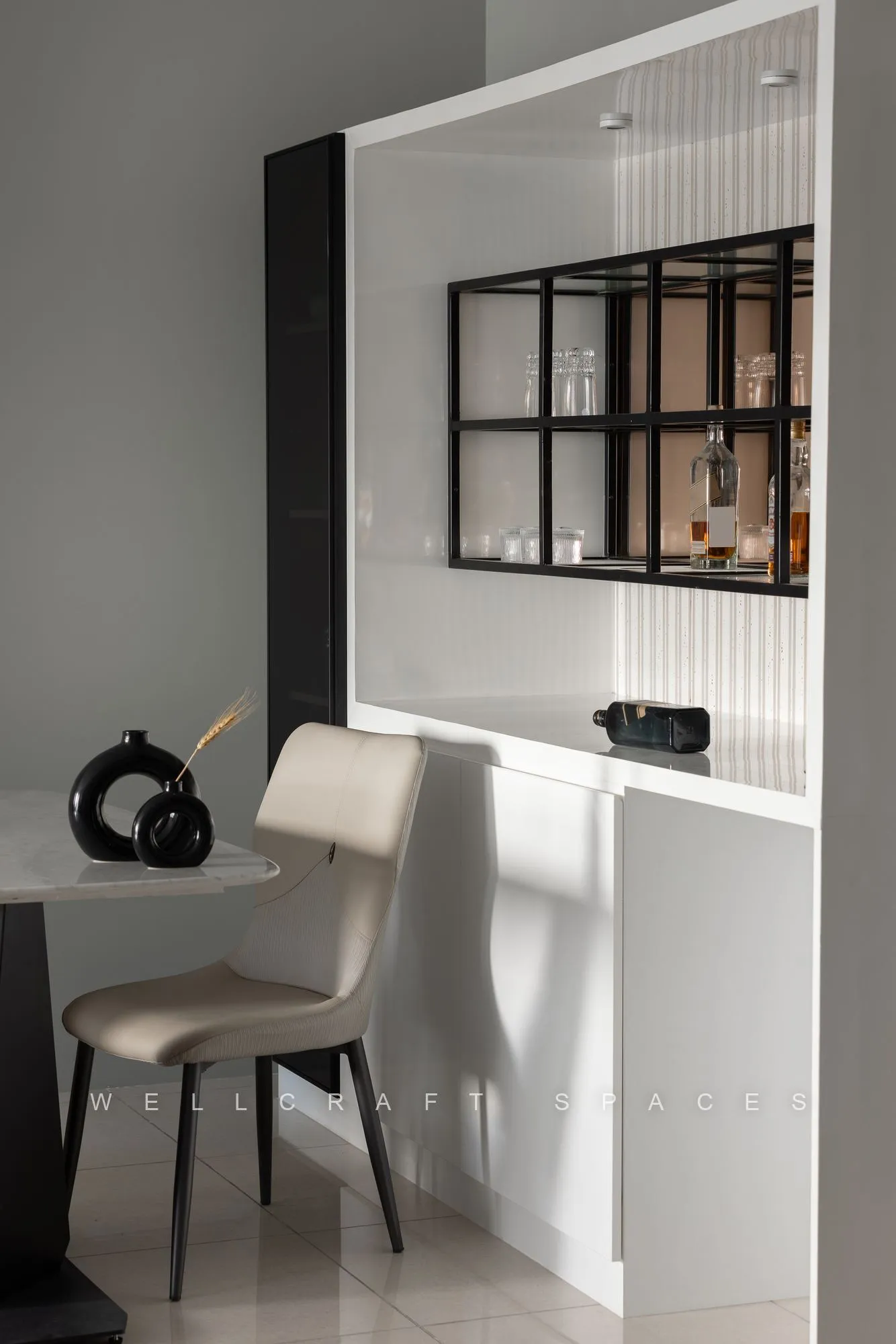 Compact desk nook with a cream counter and moulded chair set behind a black grid glass partition displaying glassware.