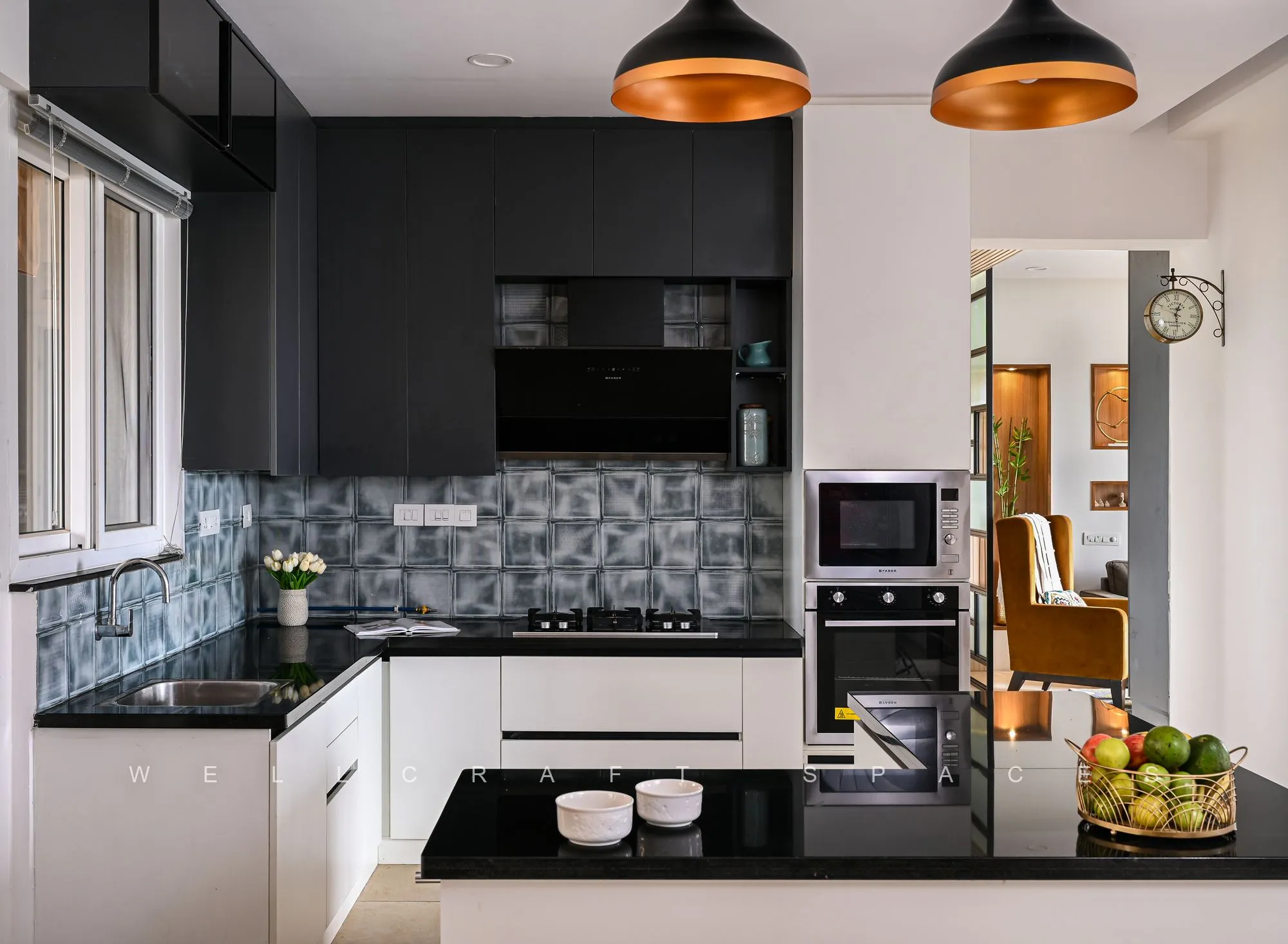 U-shaped kitchen in white and charcoal with a black stone counter, mosaic tile splashback and copper pendant lights.