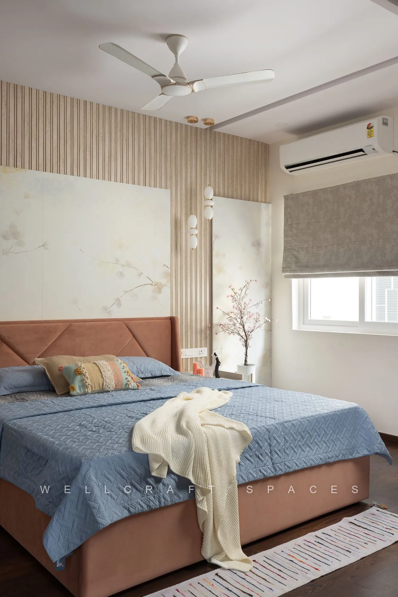 Master bedroom with a rust upholstered headboard, blue quilted bedspread and cream throw, fluted cream panelling and a delicate blossom mural.