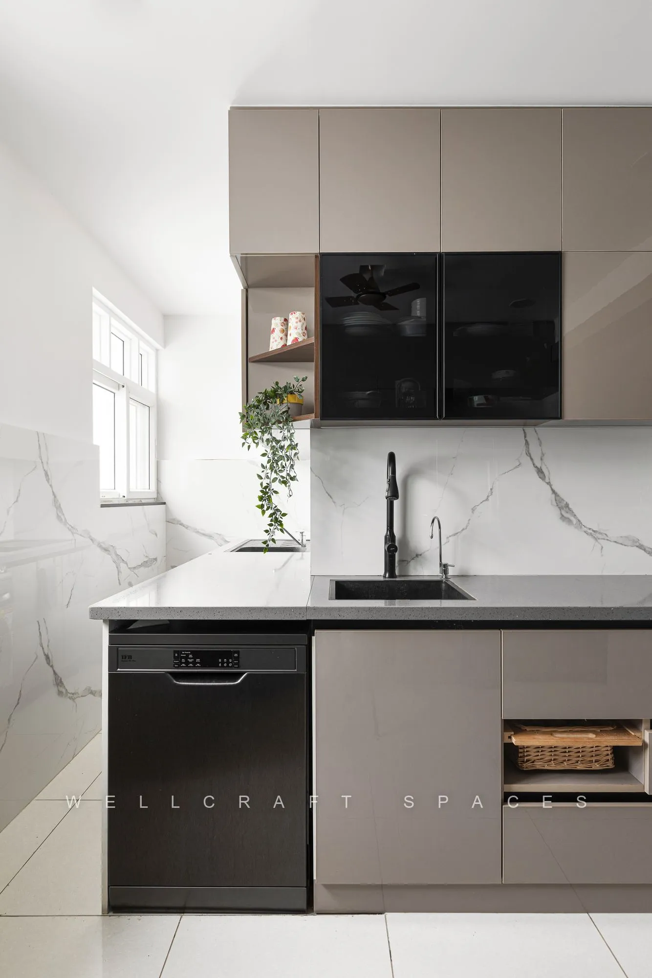 Kitchen sink run under a window with a marble-pattern backsplash, dishwasher and handleless overhead cabinets.