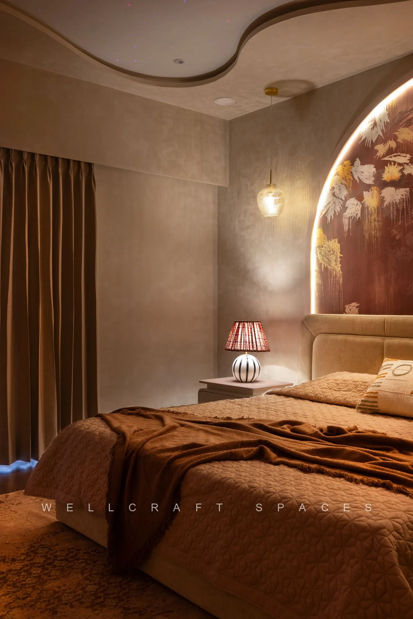 Kids bedroom with a floral arched mural behind the bed, rust quilted cover, textured plaster walls and a small table lamp.