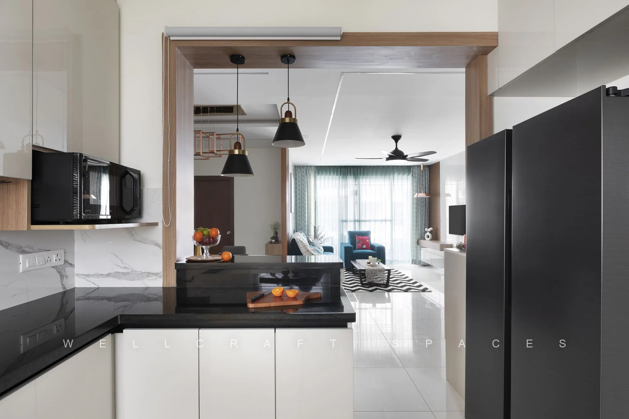 White handleless kitchen with black granite counters, a tall dark refrigerator and daylight from the utility window.
