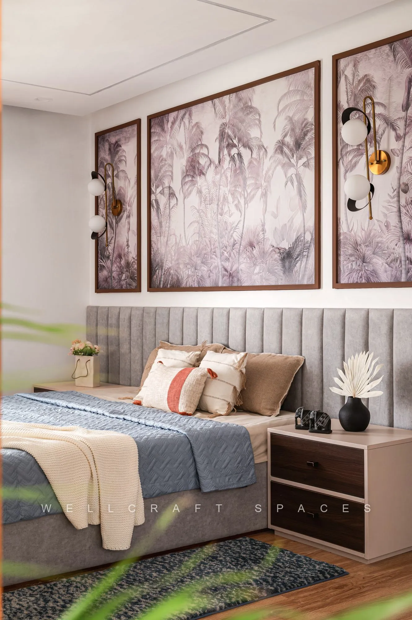 Parents' bedroom with a pale channel-tufted headboard, muted botanical artworks in dark frames and a green and grey patterned rug.
