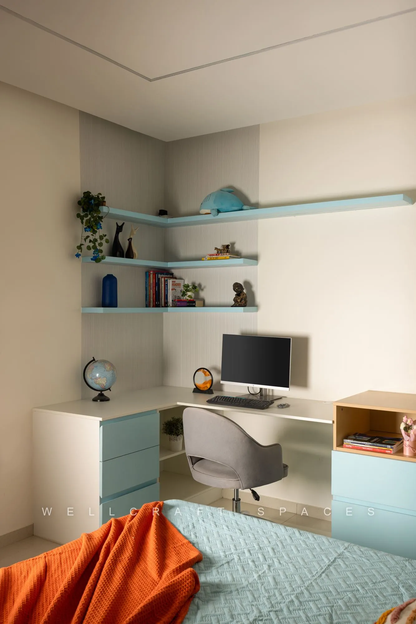 Kids study zone in mint and pale blue with floating shelves, a grey swivel chair and a rust quilted bed in the foreground.