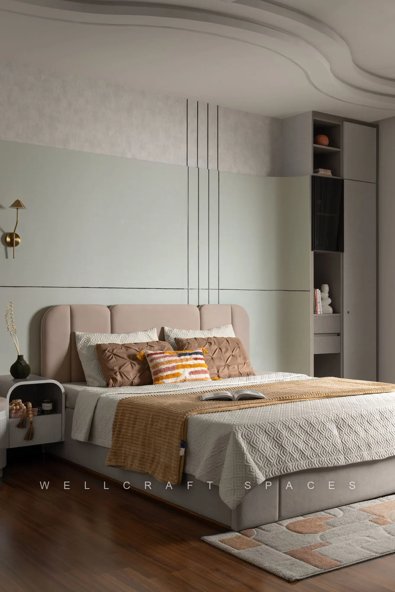 Master bedroom with a mint fluted accent wall, cushioned beige headboard, layered ochre bedding and brass wall sconces.