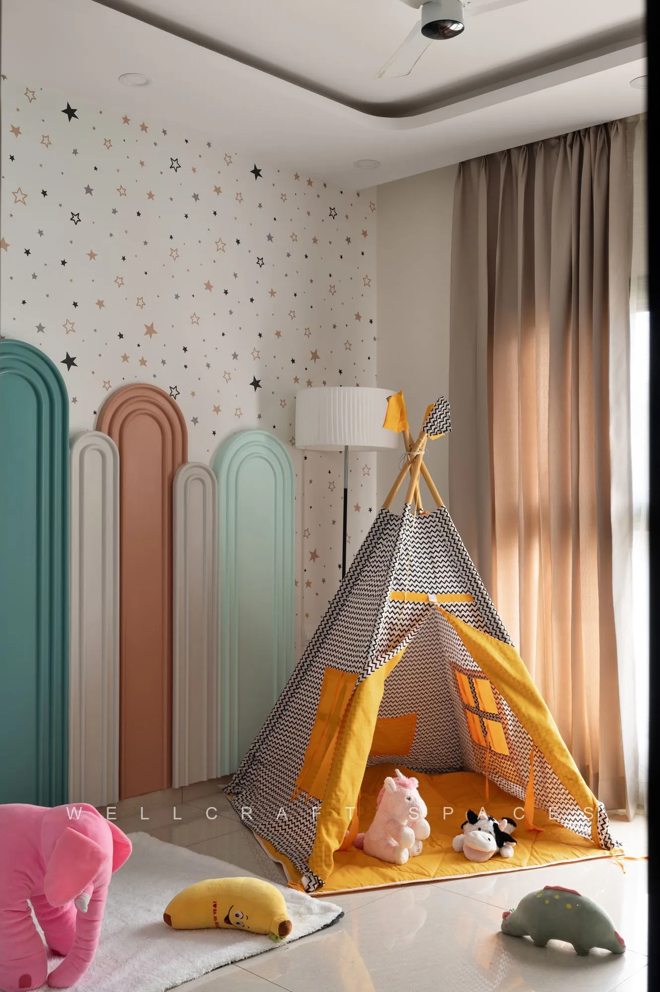 Kids room with a star-print wallpaper wall, layered mint and blush arch panels, a play teepee and soft floor cushions.