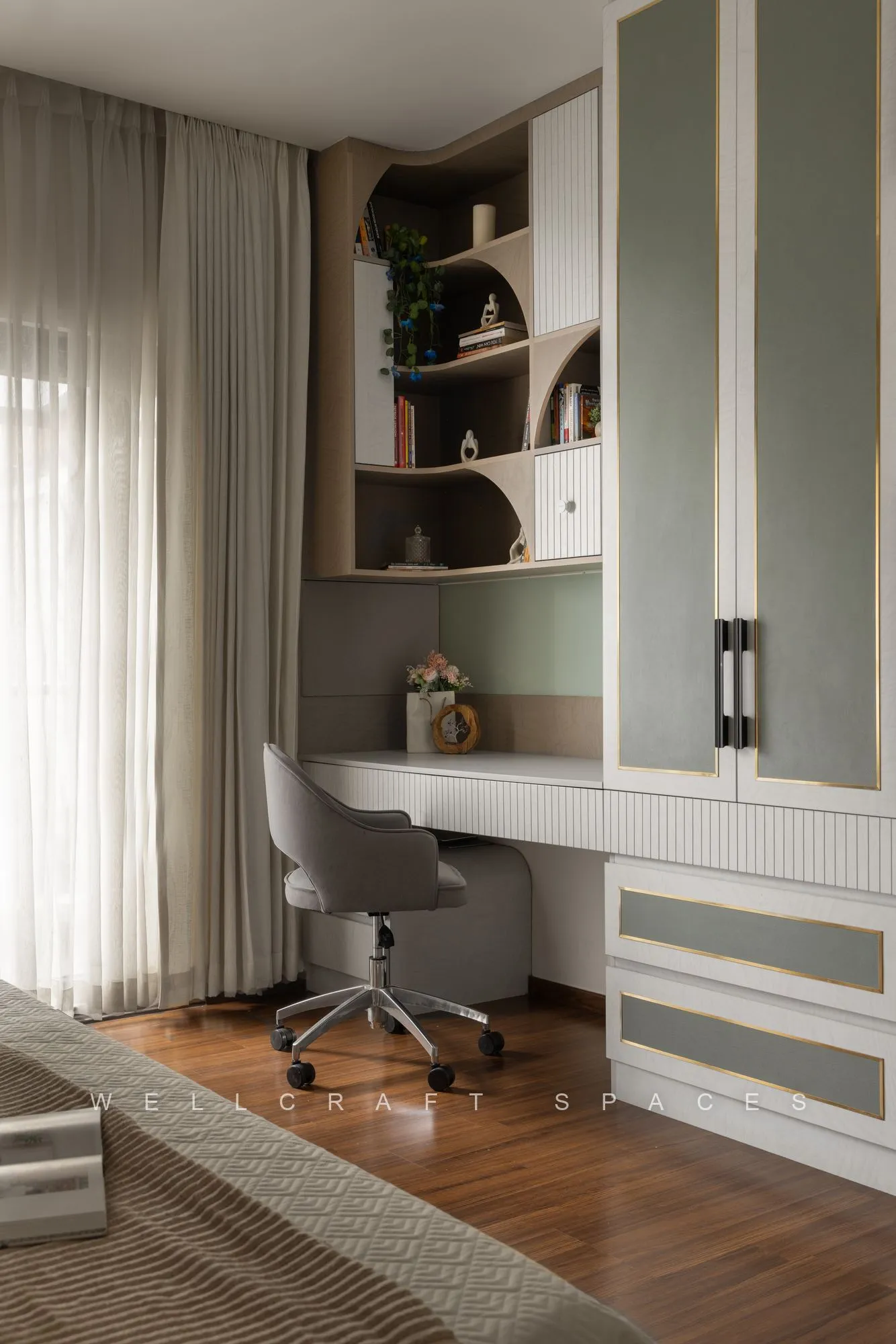 Study corner with a white fluted desk, grey swivel chair, open display shelving and a tall storage cabinet beside a curtained window.