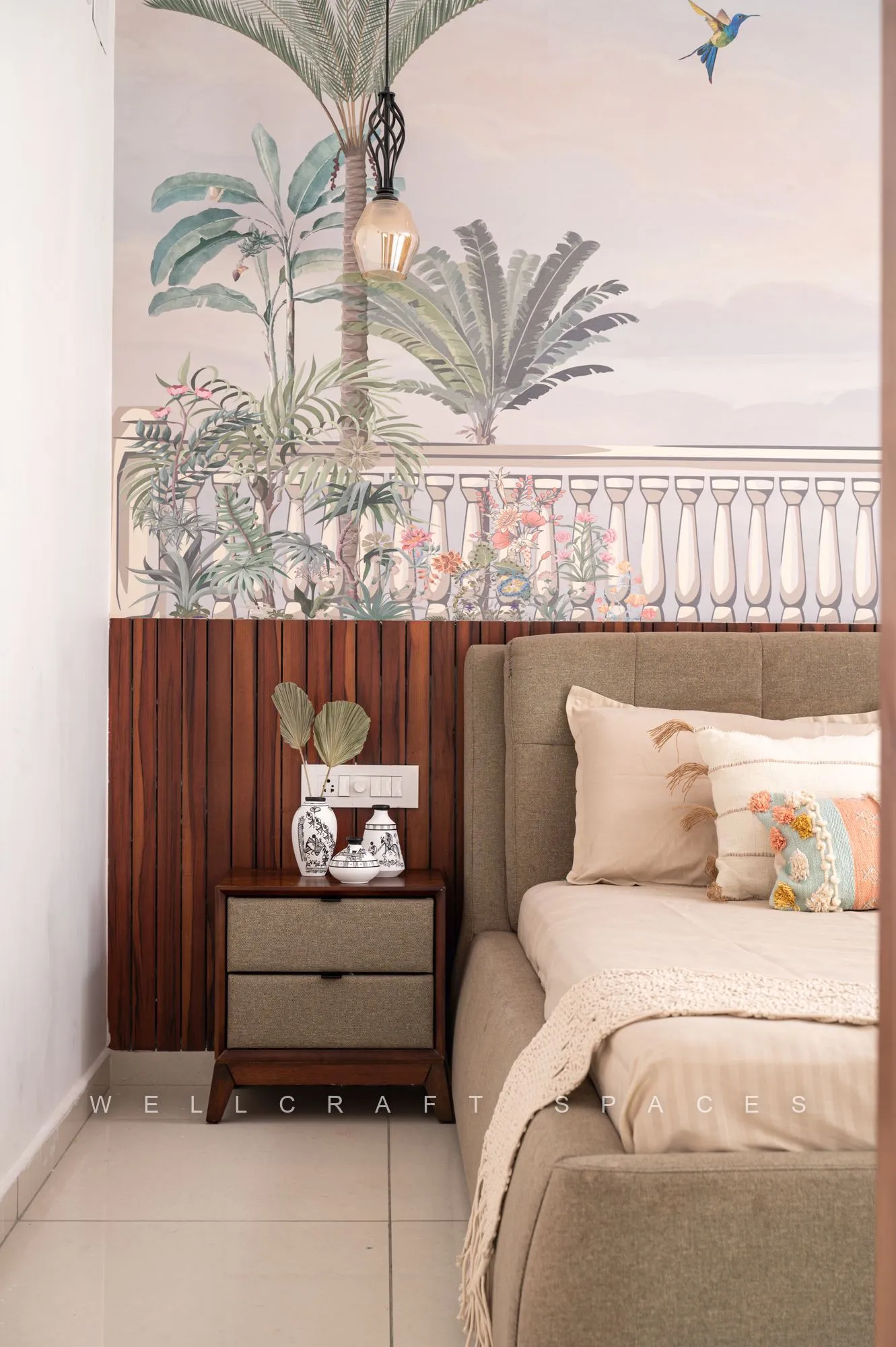 Guest bed against the painted tropical balustrade mural, with a walnut bedside drawer unit and blush and cream cushions.