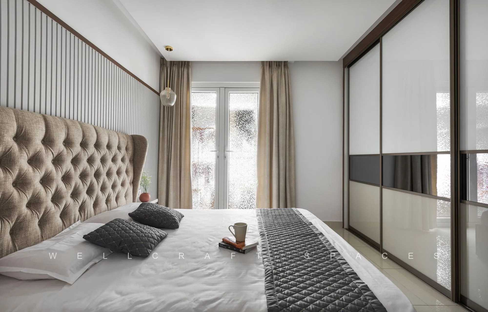 Bedroom with a buttoned beige headboard facing a full-height wardrobe with bronze mirror and cream glass shutters.