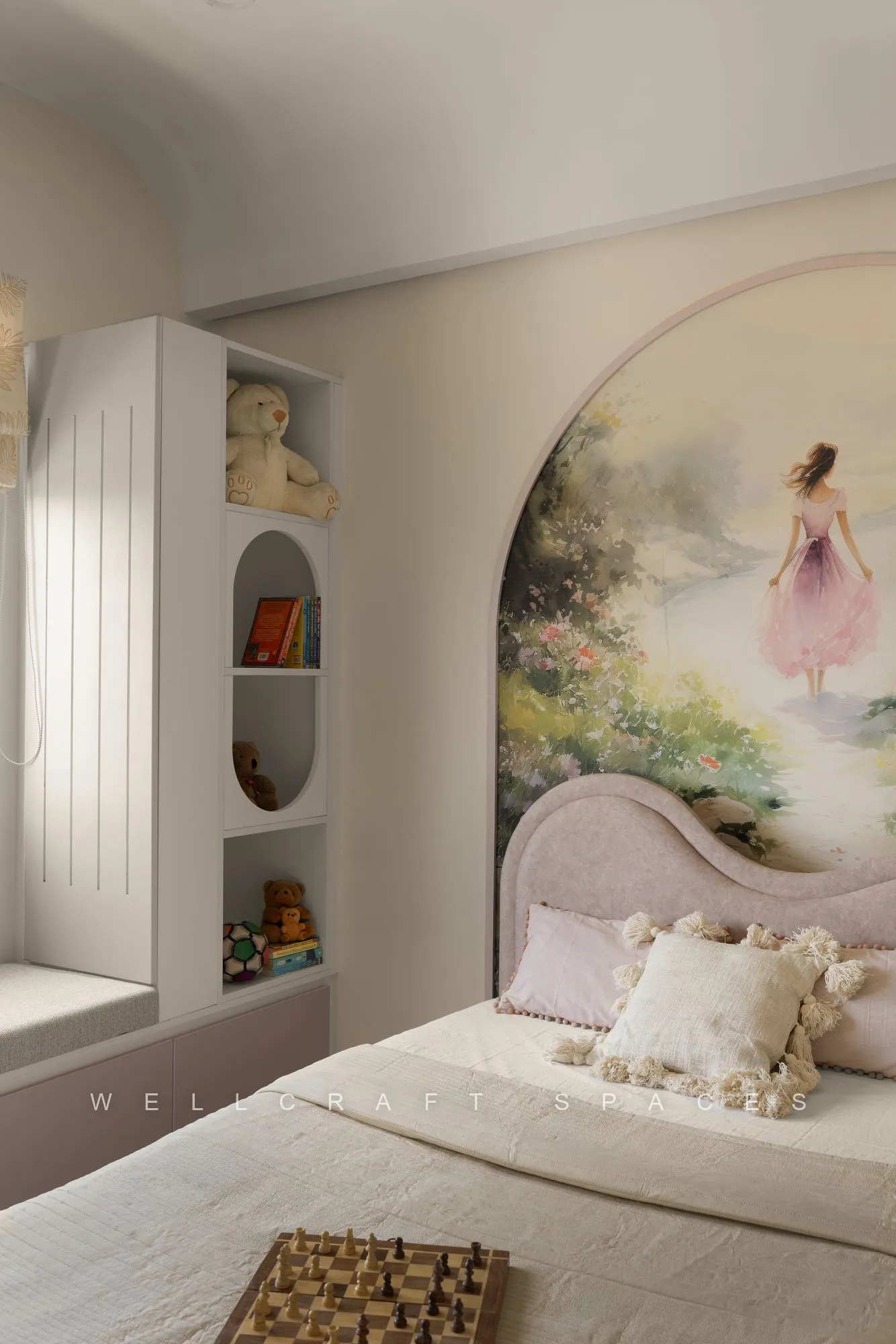 Child's bed against an arched painted mural of a girl in a garden, with a scalloped pink headboard and curved display niches.