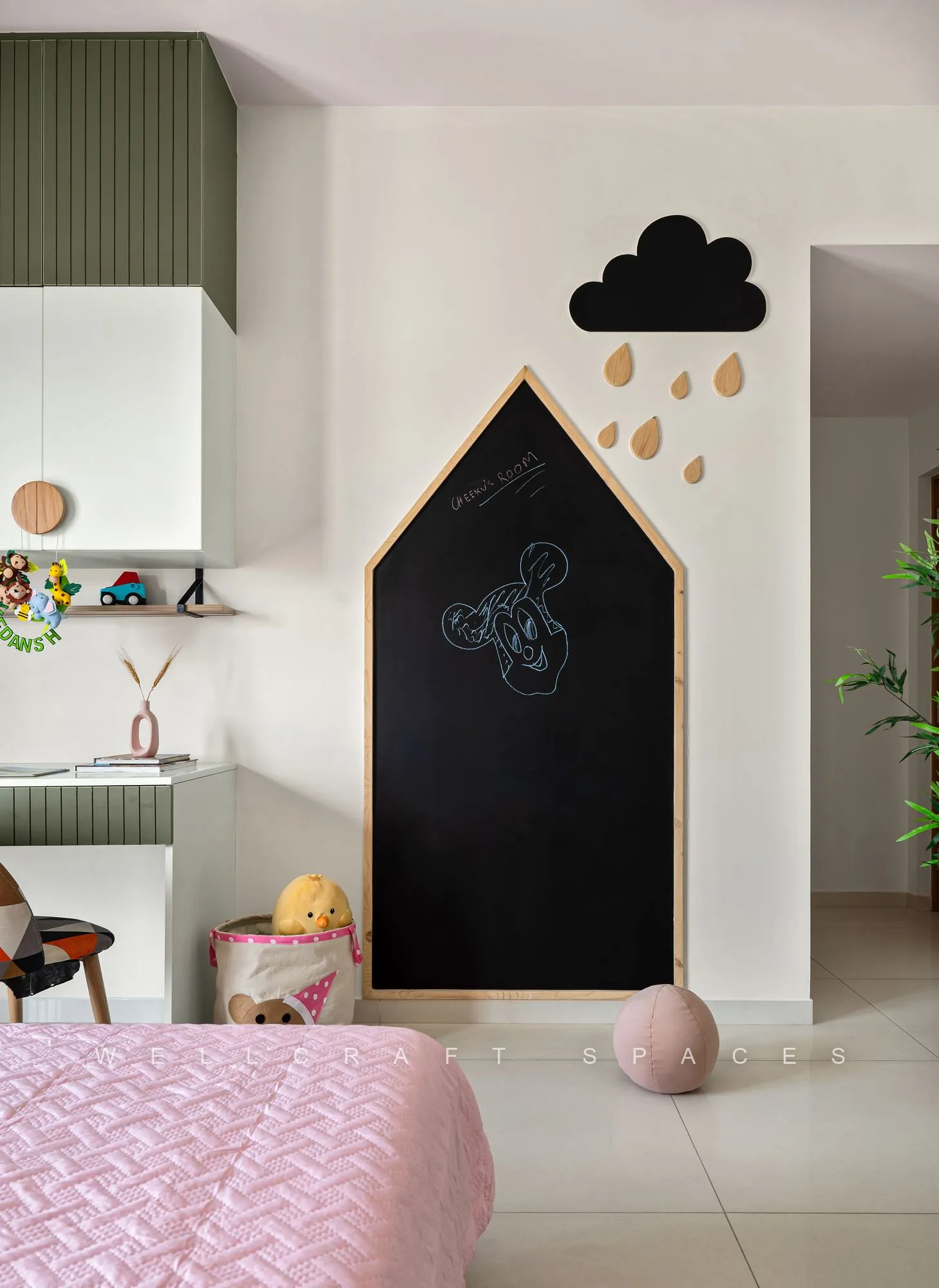 Play nook with a house-shaped chalkboard, a cloud-and-raindrop wall motif and open green shelving above the pink bed.
