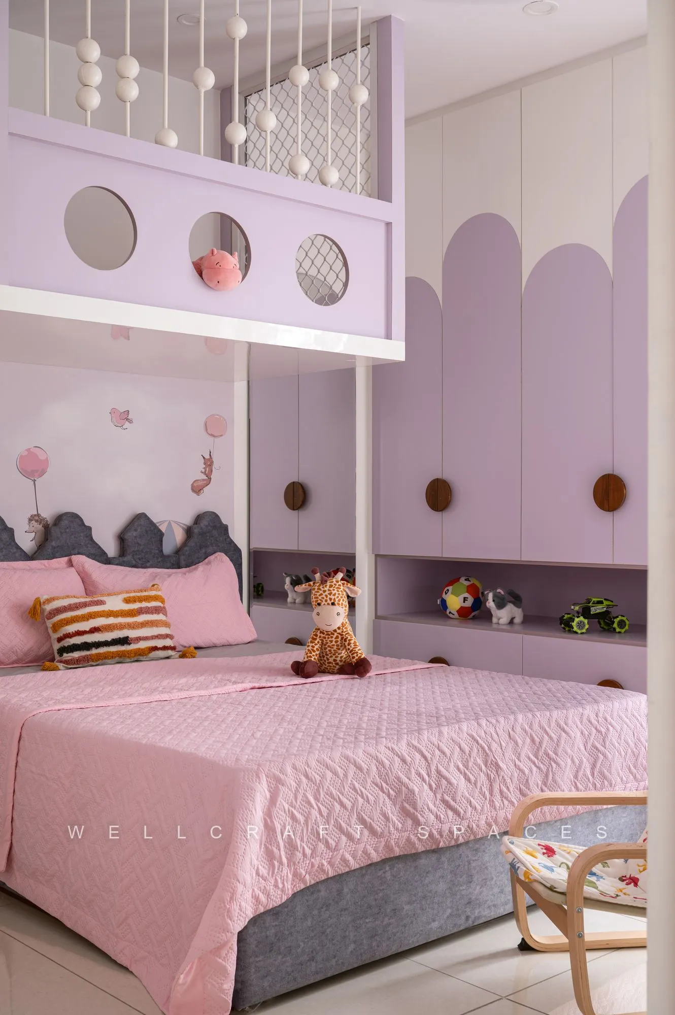 Girl's room in lilac and pink with a scalloped loft bunk, porthole cut-outs, macrame pendants and a pink quilted bed below.