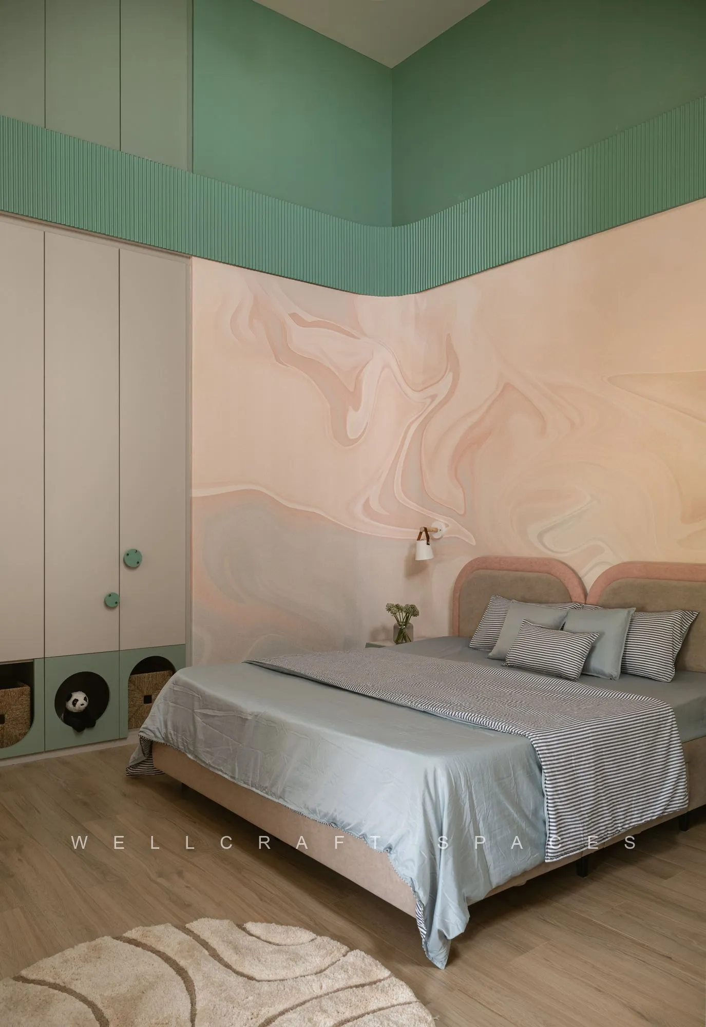 Kids room with a mint painted ceiling drop, blush marbled headboard wall, pale wood flooring and a soft green bedspread.