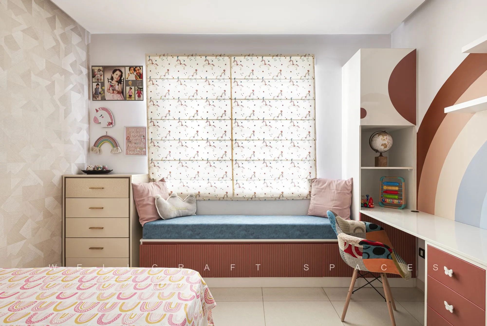 Child's room with a painted rainbow arch headboard wall, a cushioned window seat in blue and a compact study desk.