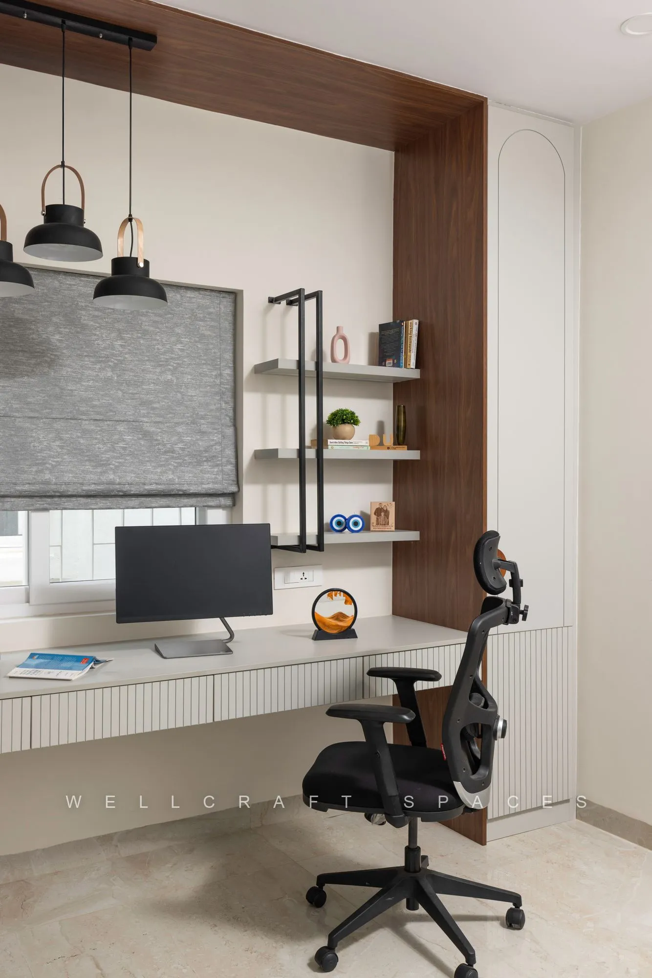 Home office with a long white fluted desk under a walnut-lined niche, black dome pendants, open shelves and an ergonomic mesh chair.