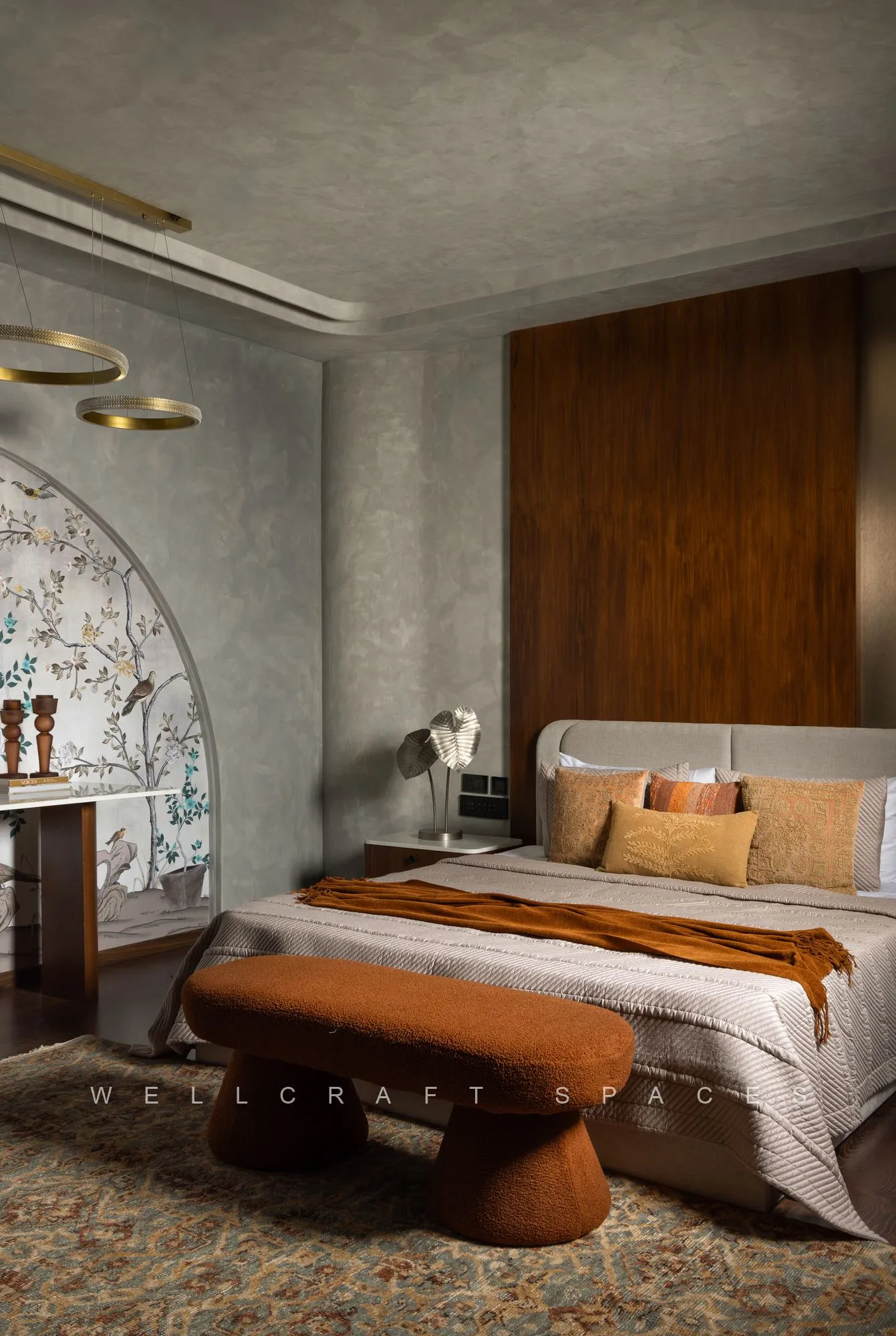 Master bedroom with a walnut headboard wall, an arched chinoiserie mural beside the writing desk, a rust bouclé pebble bench and terracotta cushions on the bed.